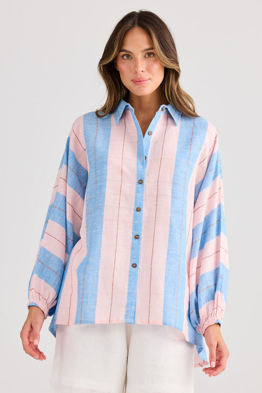 Woman wearing a colorful striped shirt and white shorts on a plain background