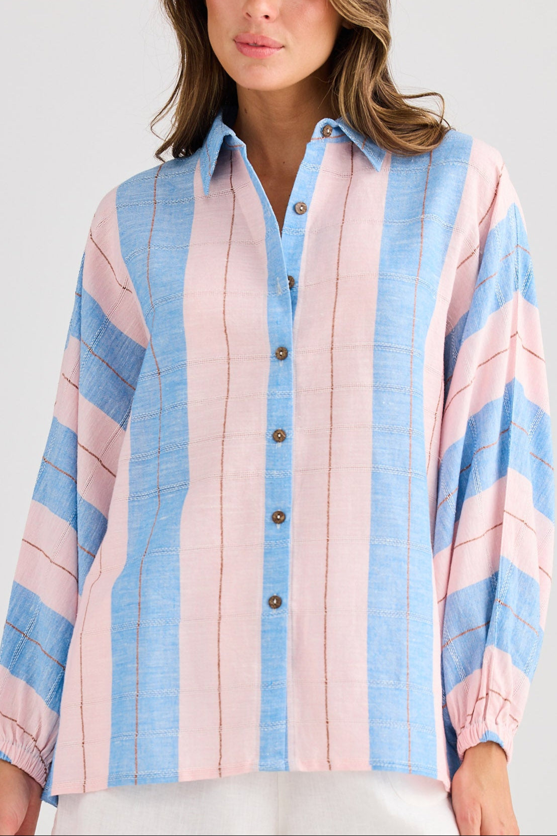 Woman wearing a colorful striped shirt and white shorts on a plain background