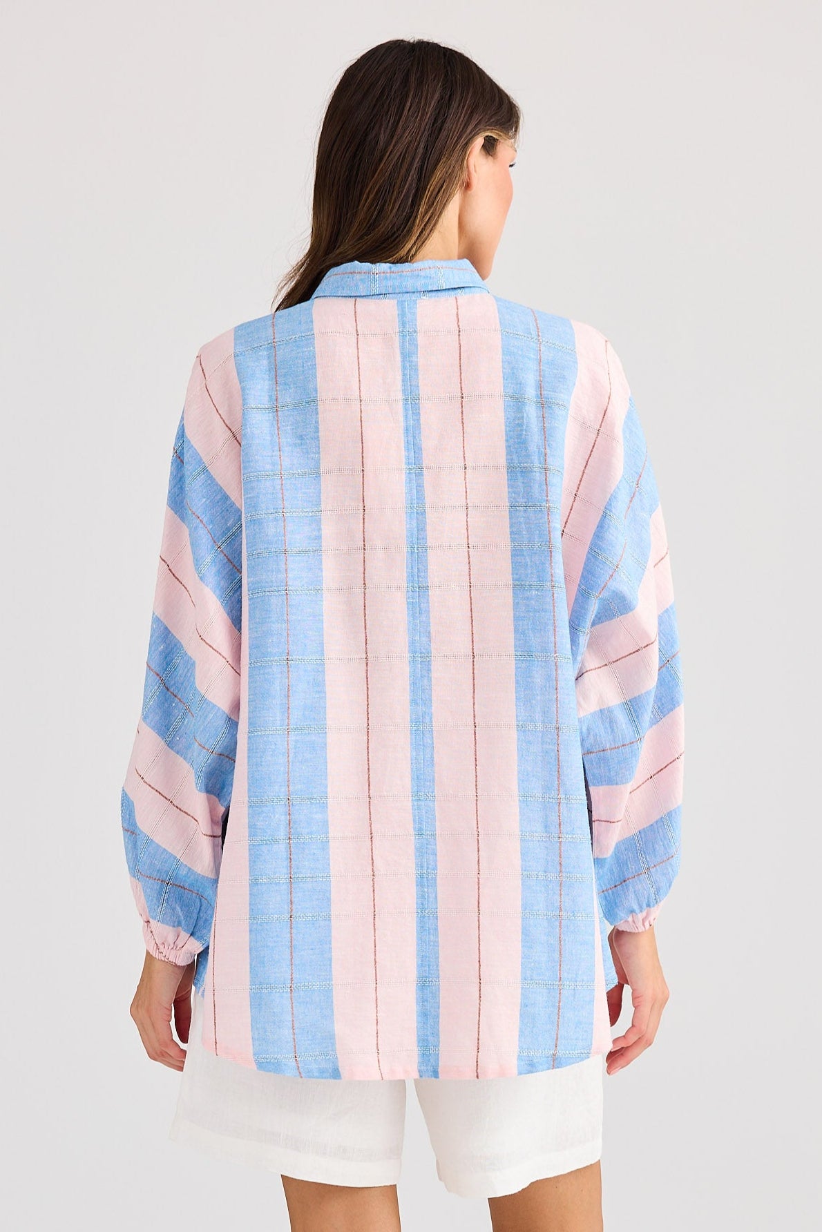 Person wearing a striped shirt with pastel colors on a plain background