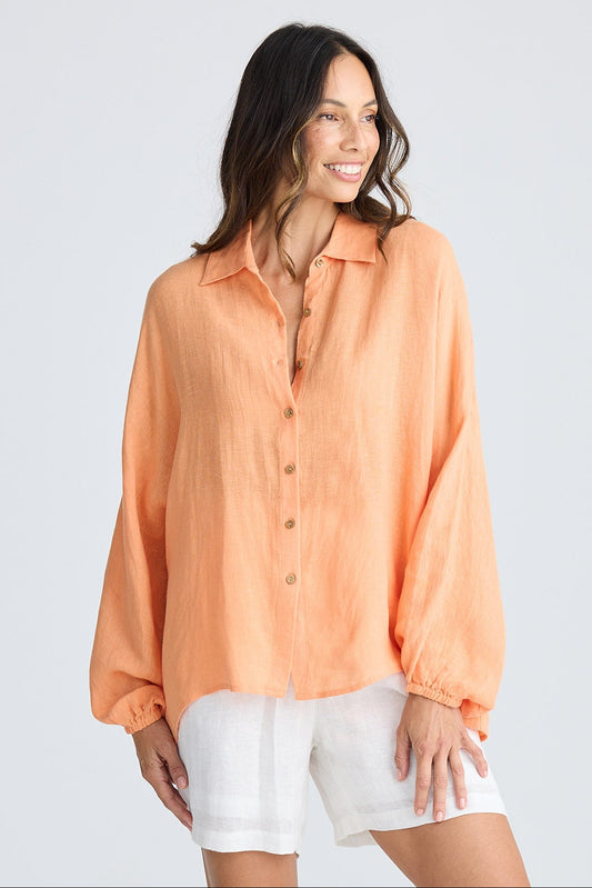 Woman wearing an orange shirt and white shorts on a plain background