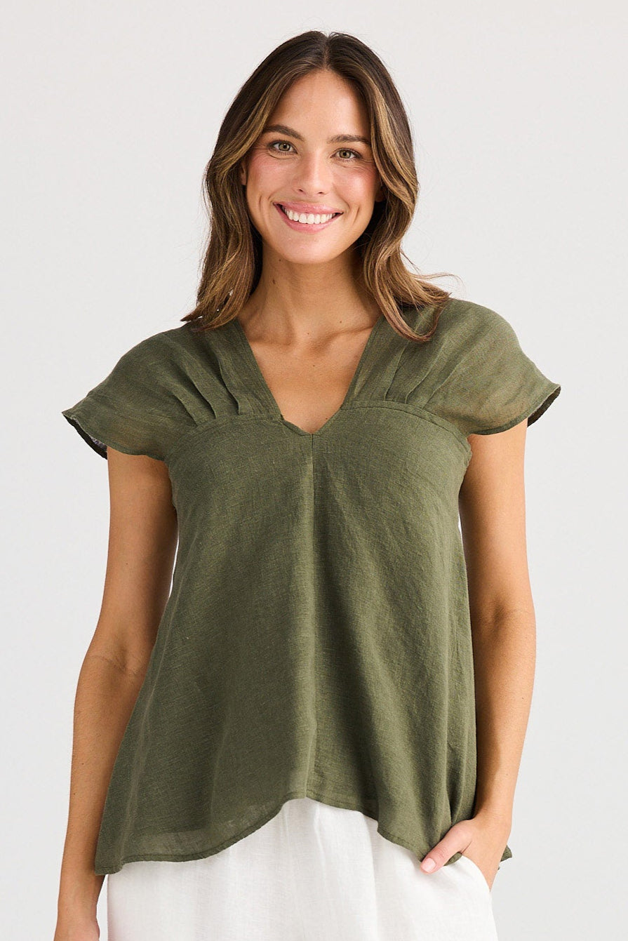 Woman wearing a green top and white pants on a white background