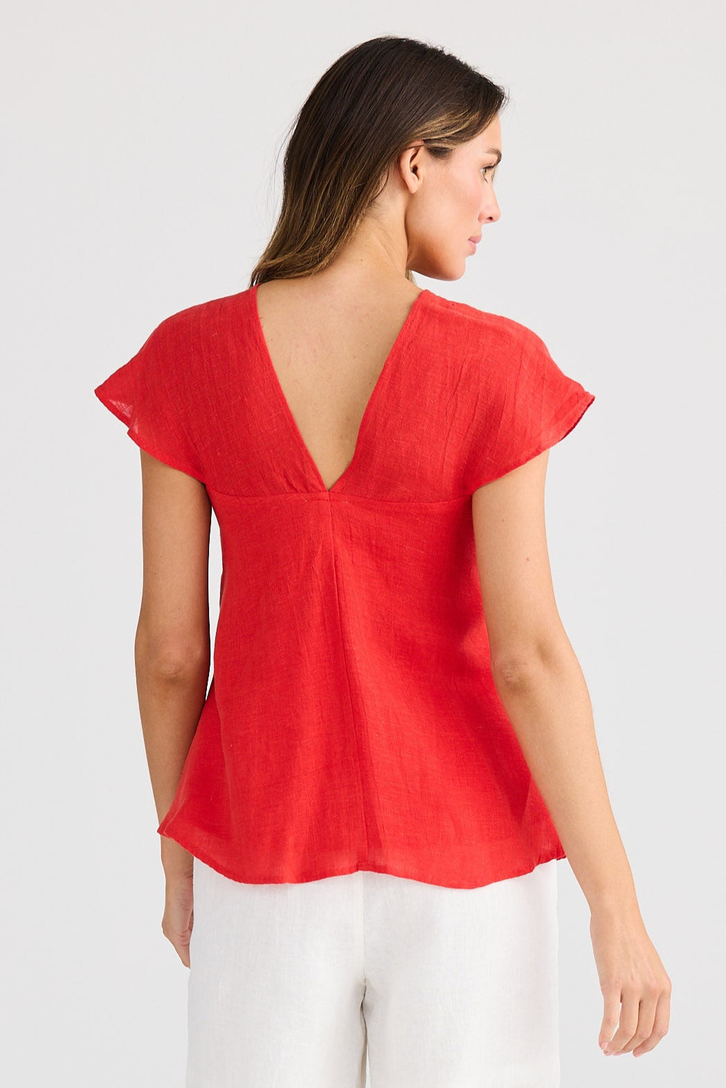 Woman wearing a red top and white shorts on a white background