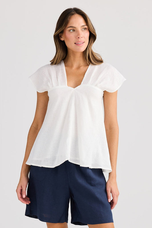 Woman wearing a white blouse and navy shorts on a light gray background