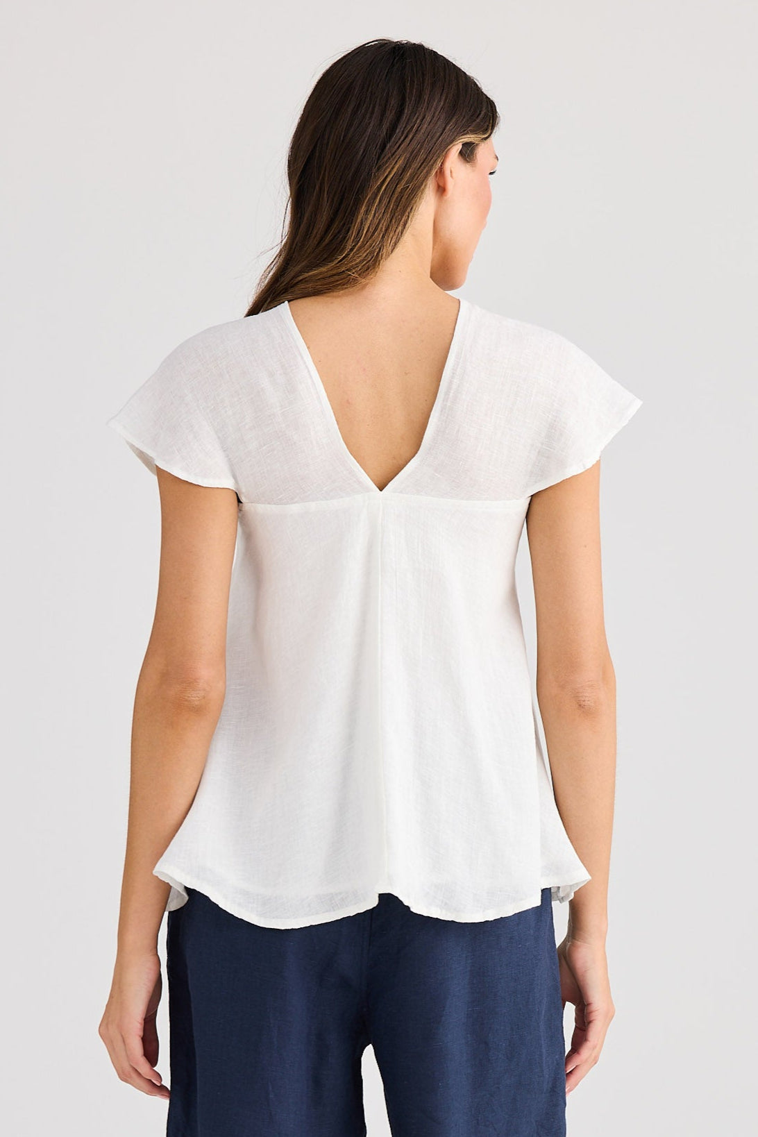 Woman wearing a white blouse and navy shorts on a plain background