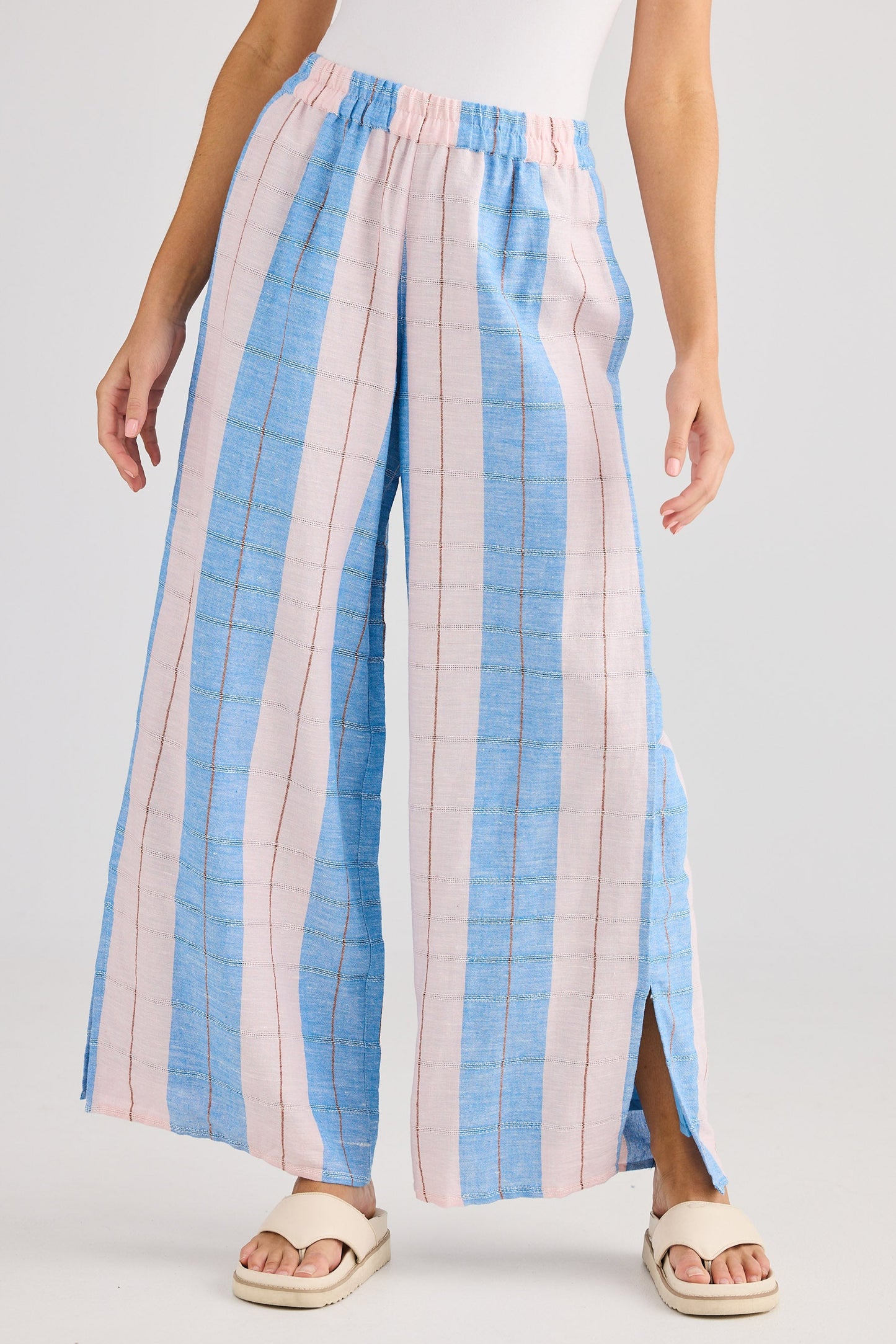 Woman wearing a white top and blue and pink striped pants on a white background