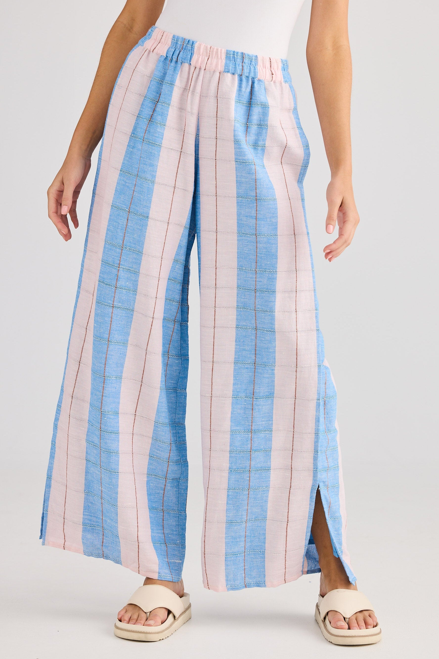 Woman wearing a white top and blue and pink striped pants on a white background
