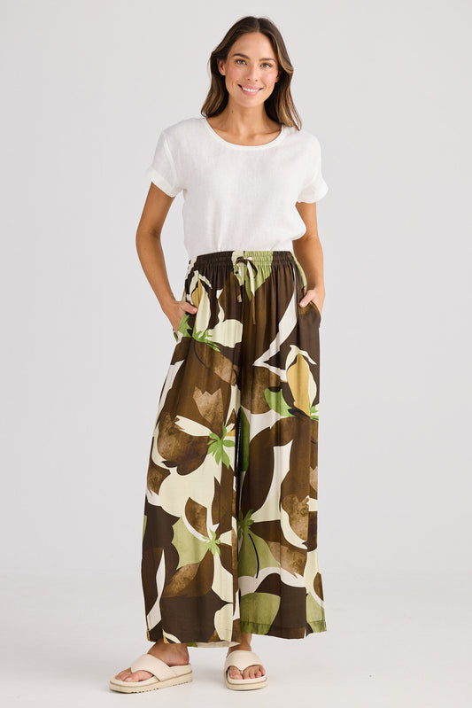 Woman wearing a white top and floral skirt on a plain background
