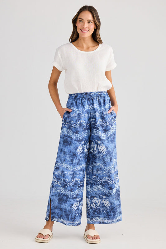 Woman wearing a white t-shirt and blue patterned pants on a white background