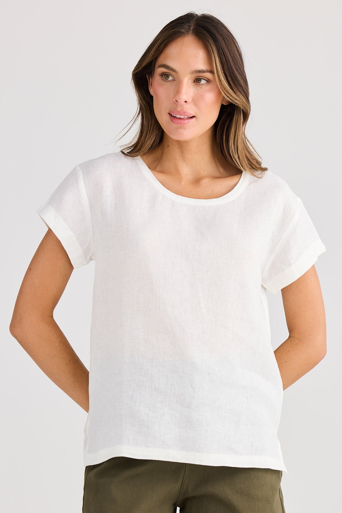 Woman wearing a white t-shirt and green shorts on a plain background