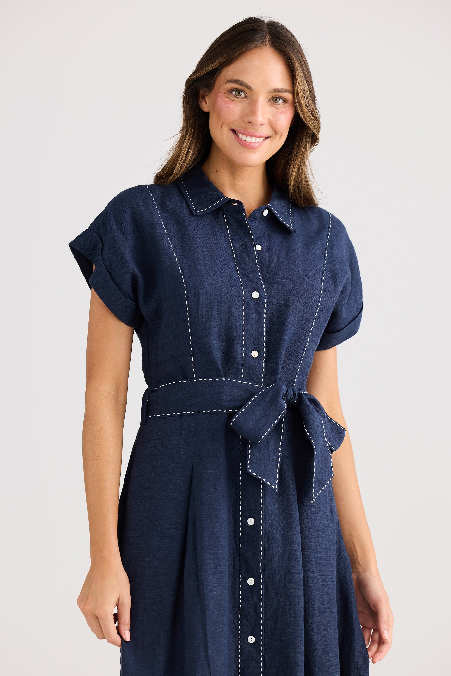 Woman wearing a navy blue dress with a belt on a white background