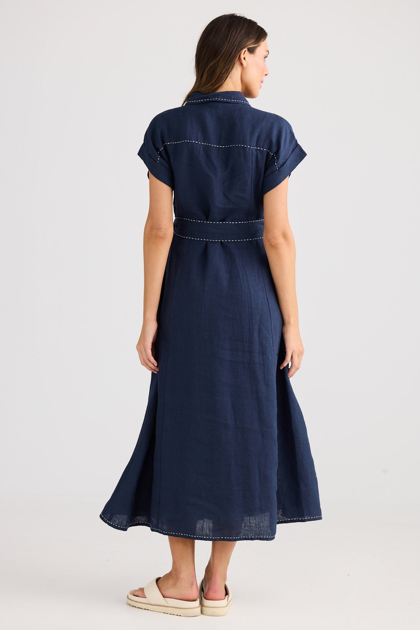 Woman wearing a navy blue dress with a belt on a white background