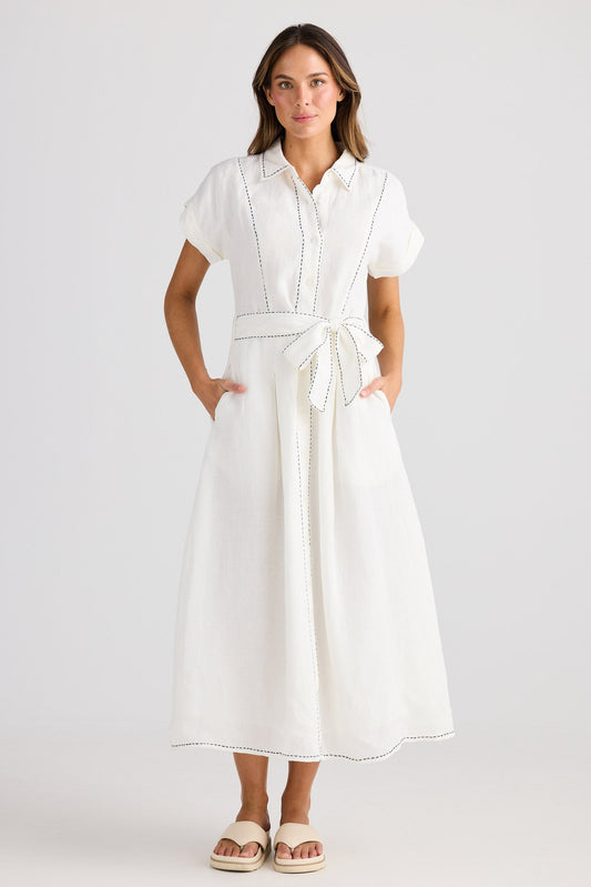 Woman wearing a white dress with a belt on a plain background