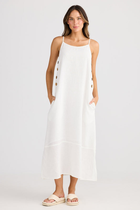 Woman wearing a white sleeveless dress with buttons on a plain background