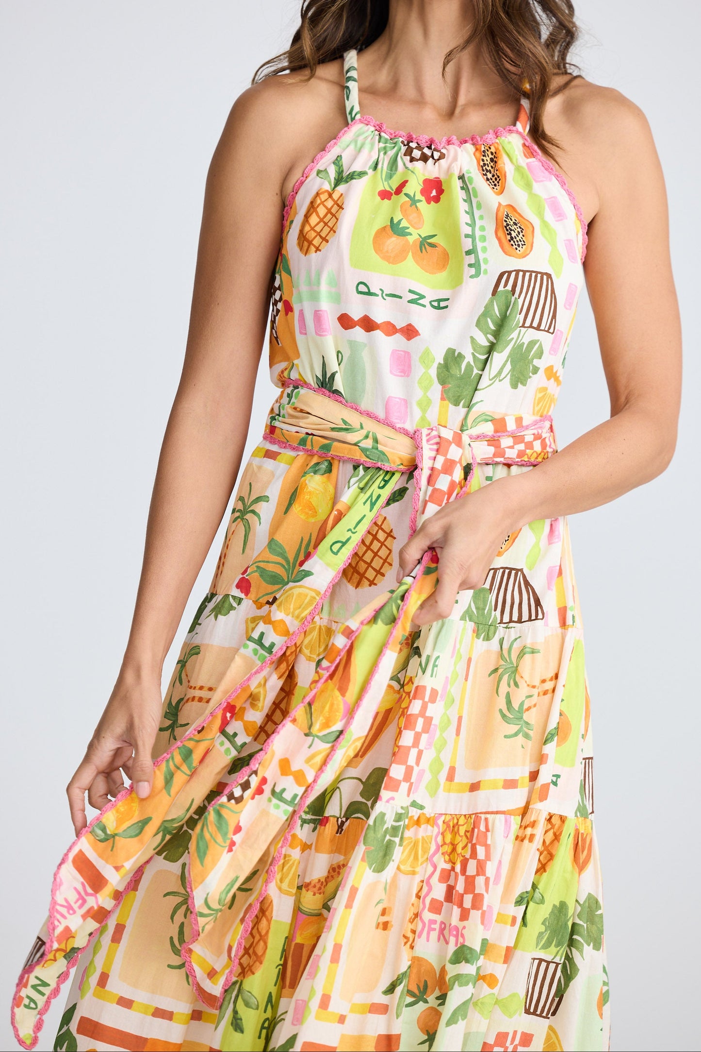 Woman wearing a colorful dress with fruit pattern on a plain background
