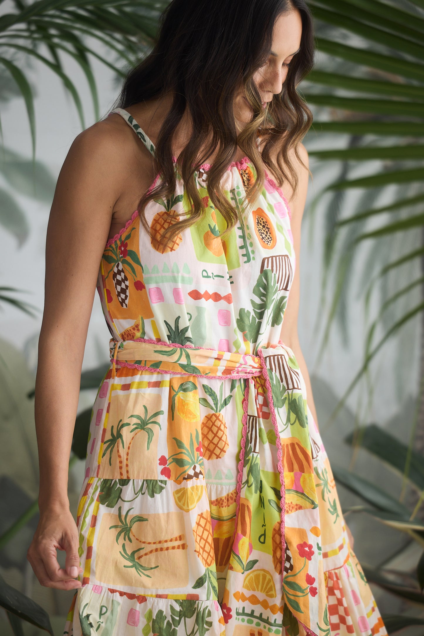 Woman wearing a colorful pineapple patterned dress with greenery in the background
