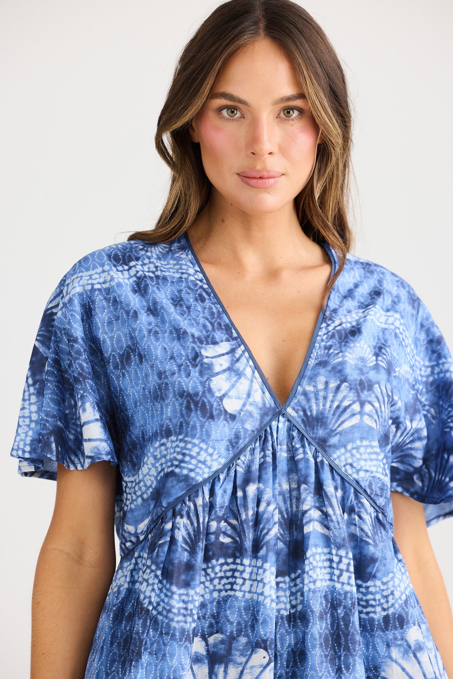 Woman wearing a blue patterned dress against a white background