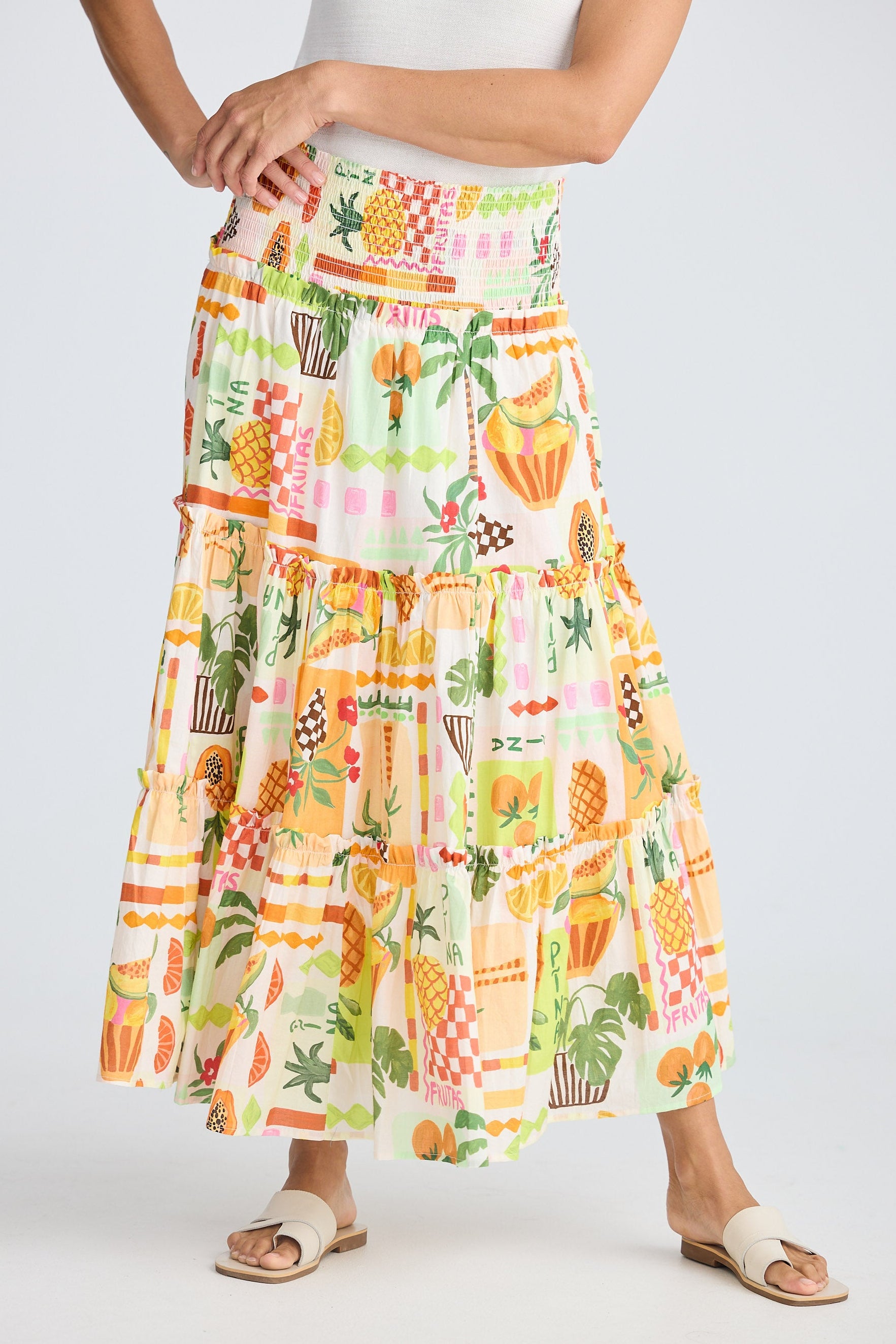 Person wearing a colorful fruit print skirt on a white background