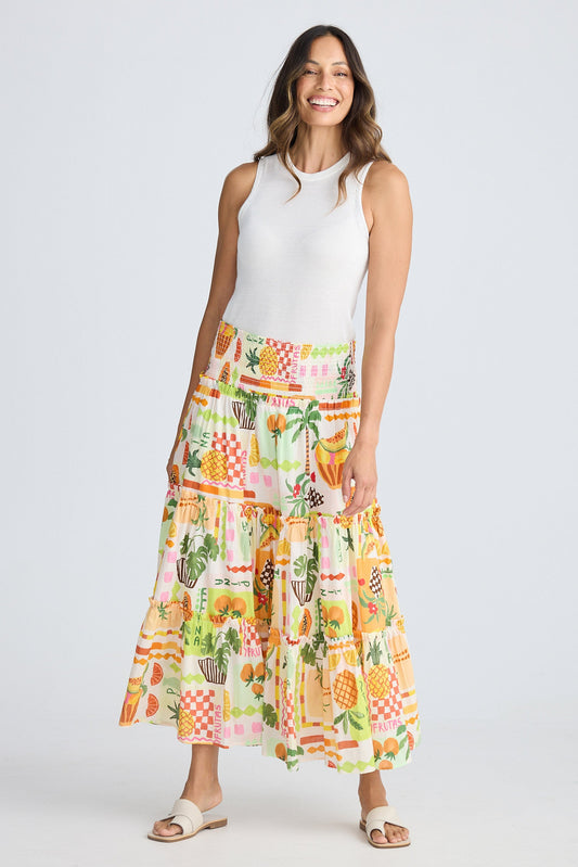 Woman wearing a white sleeveless top and colorful patterned skirt on a white background