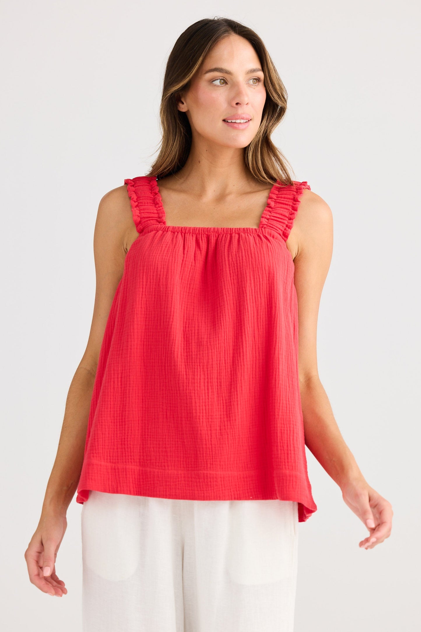 Woman wearing a red sleeveless top with ruffled straps on a white background