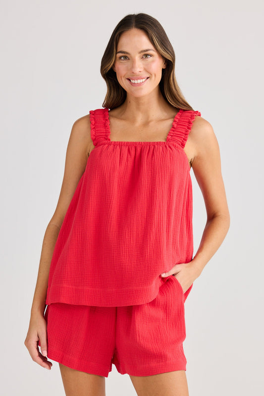 Woman wearing a red top and shorts set on a plain background