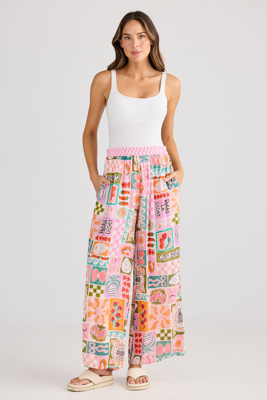 Woman wearing a white tank top and colorful patterned pants on a white background