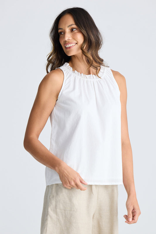 Woman wearing a white sleeveless top and beige skirt on a white background