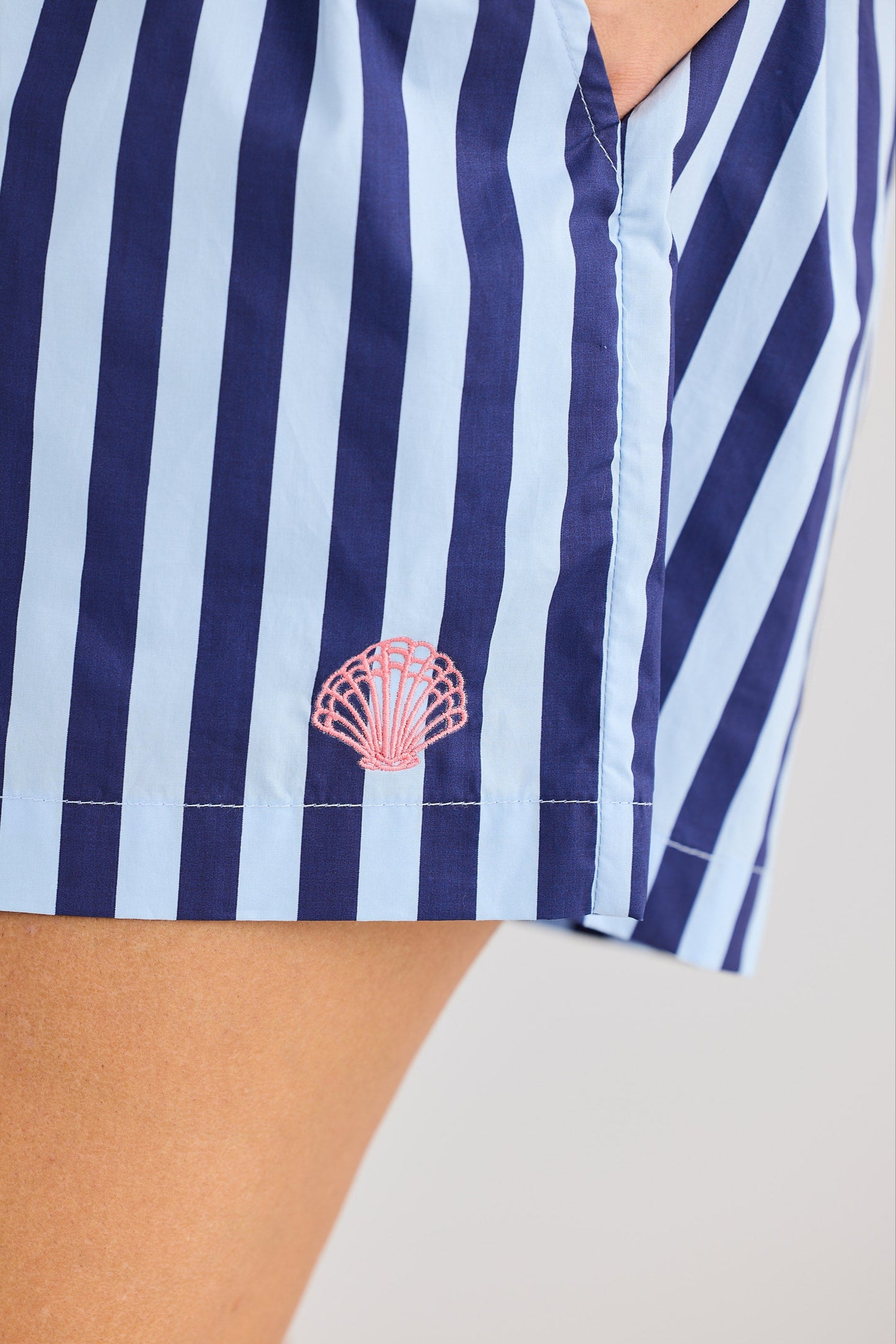 Navy and white striped shirt with a pink shell design on a beige background