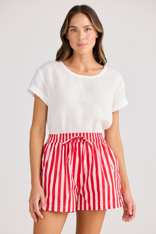 Woman wearing a white top and red striped shorts on a plain background
