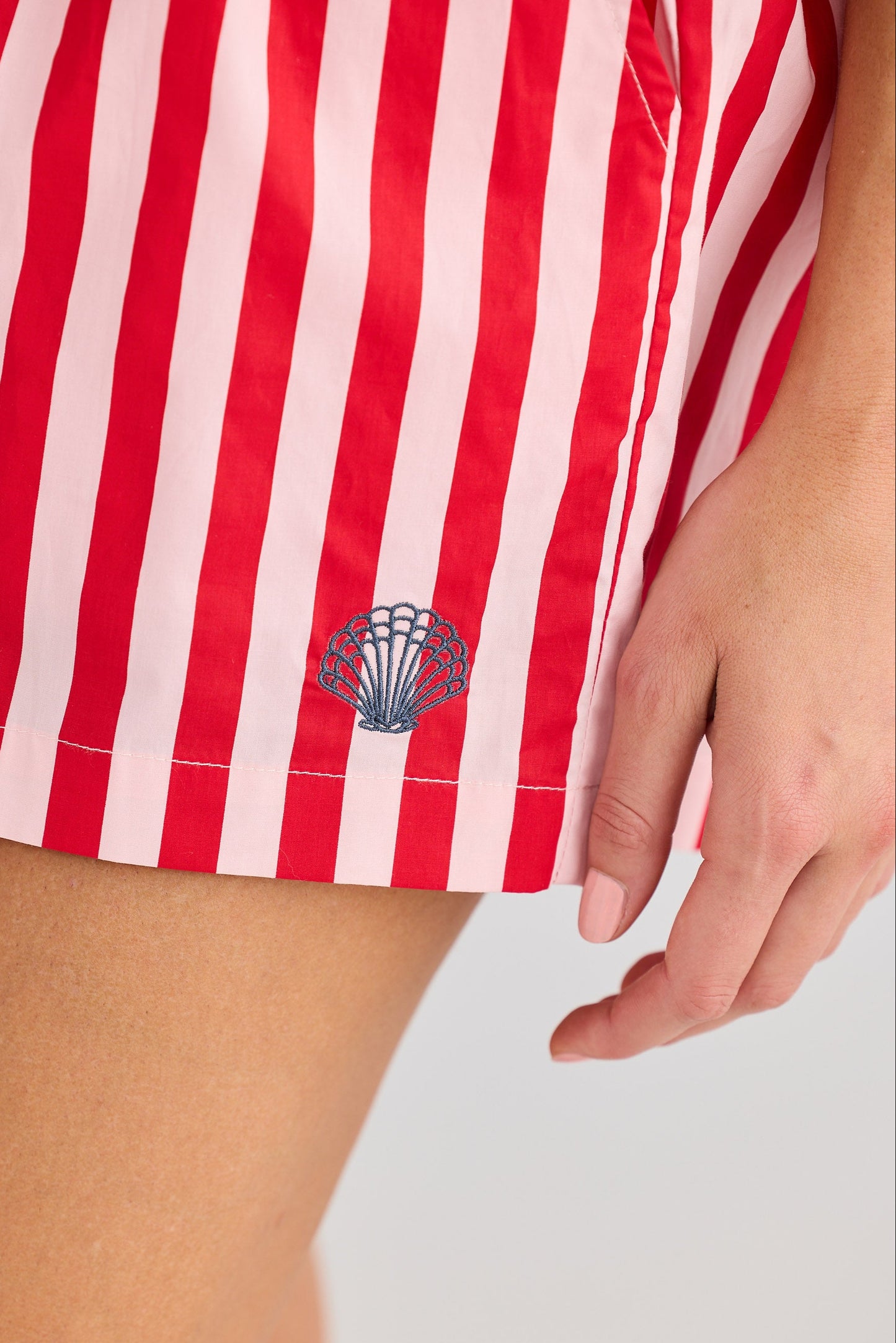Red and white striped shorts with a shell logo on a light gray background