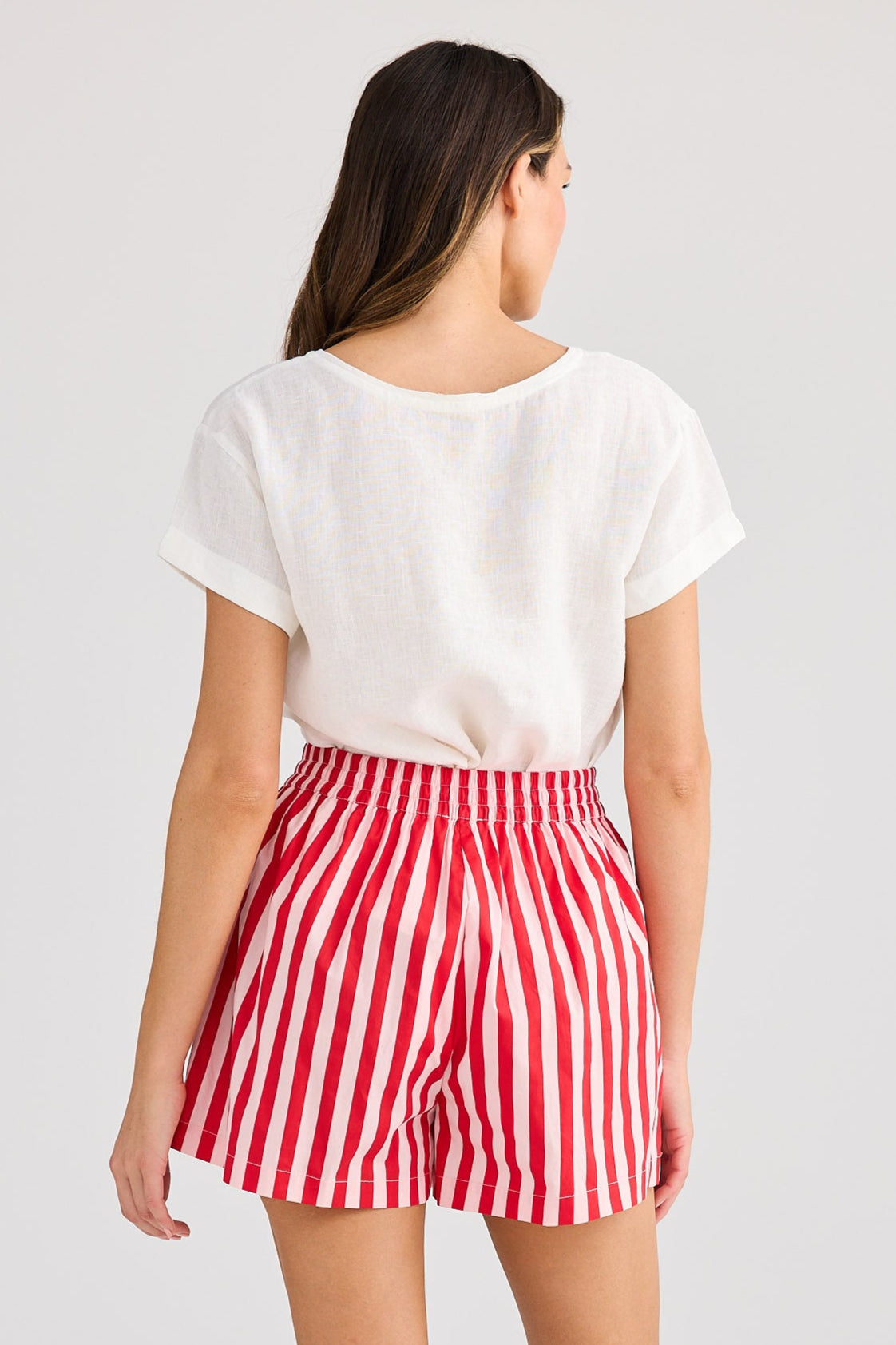 Person wearing a white t-shirt and red and white striped shorts on a plain background