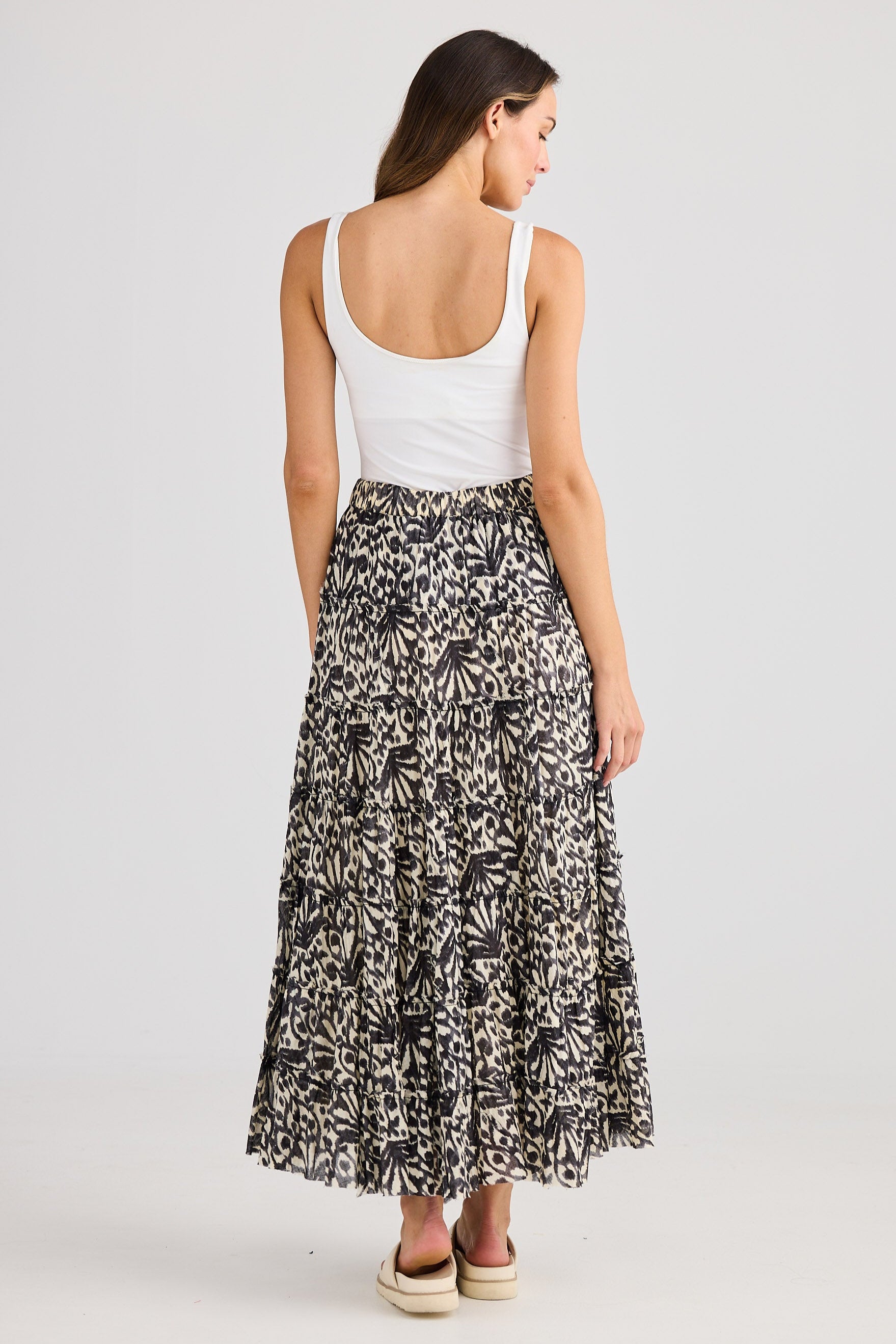 Woman wearing a white top and patterned skirt on a plain background