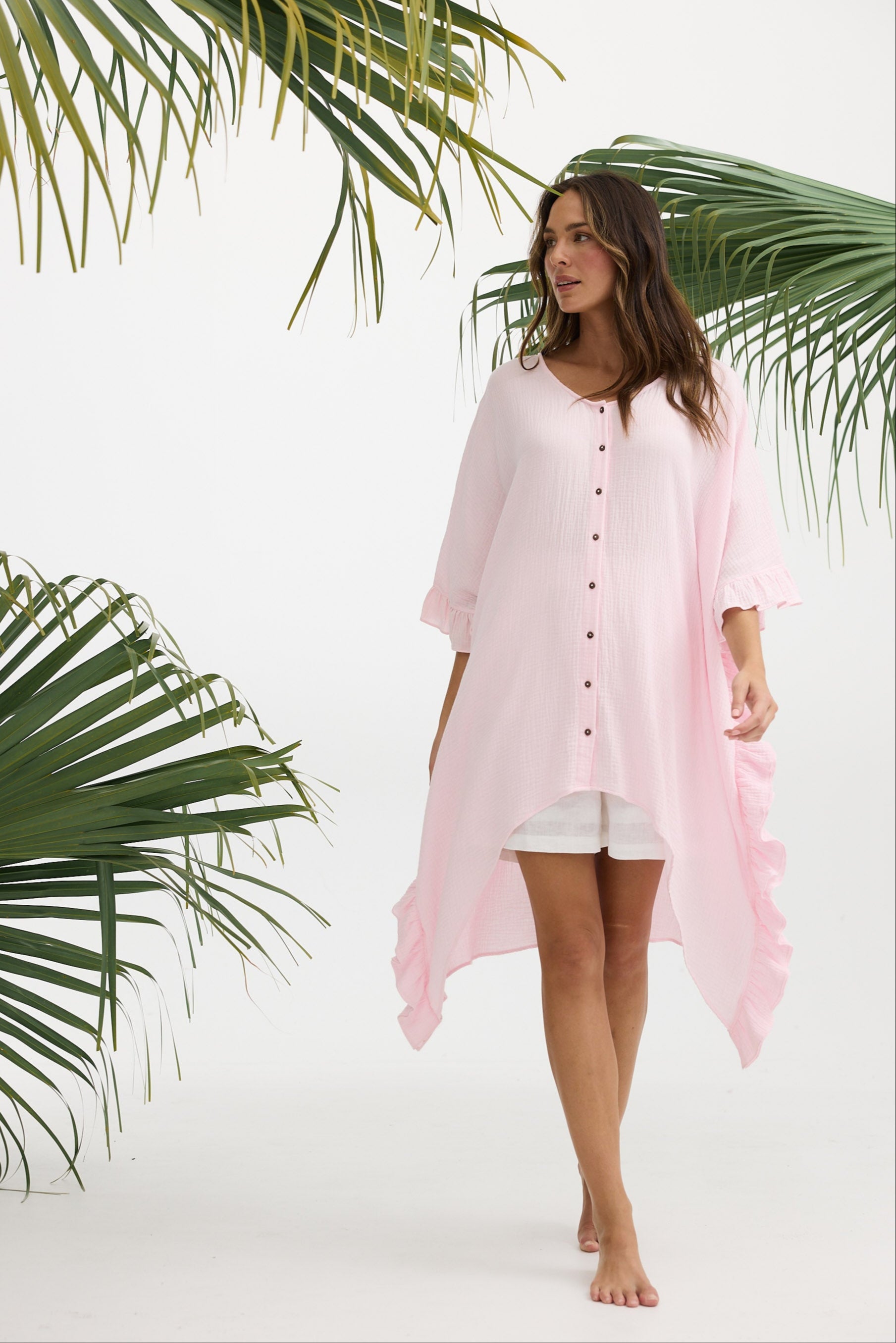 Woman wearing a pink cover-up with palm leaves in the background