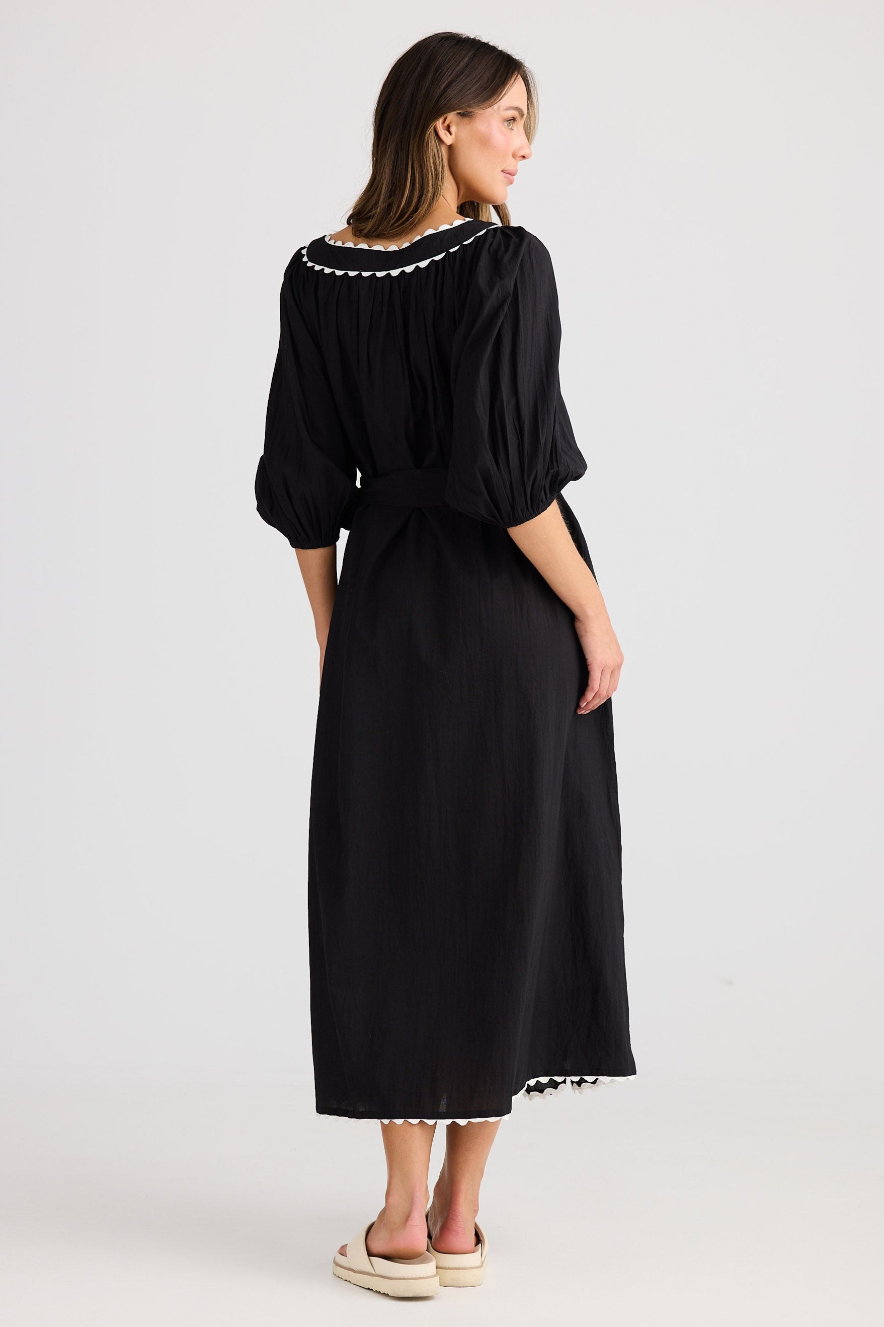 Woman wearing a black dress with white trim on a white background