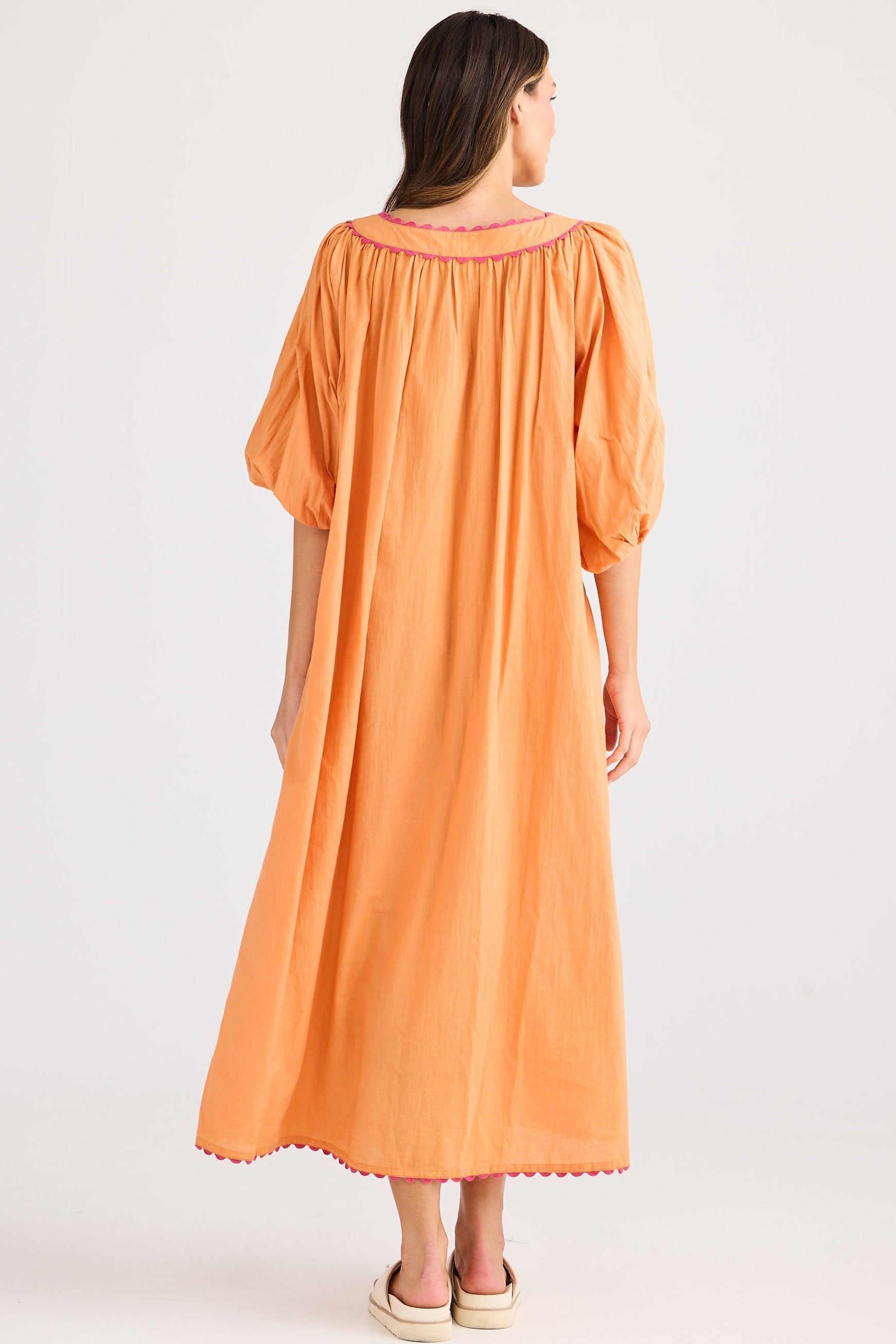 Woman wearing an orange dress with a plain background