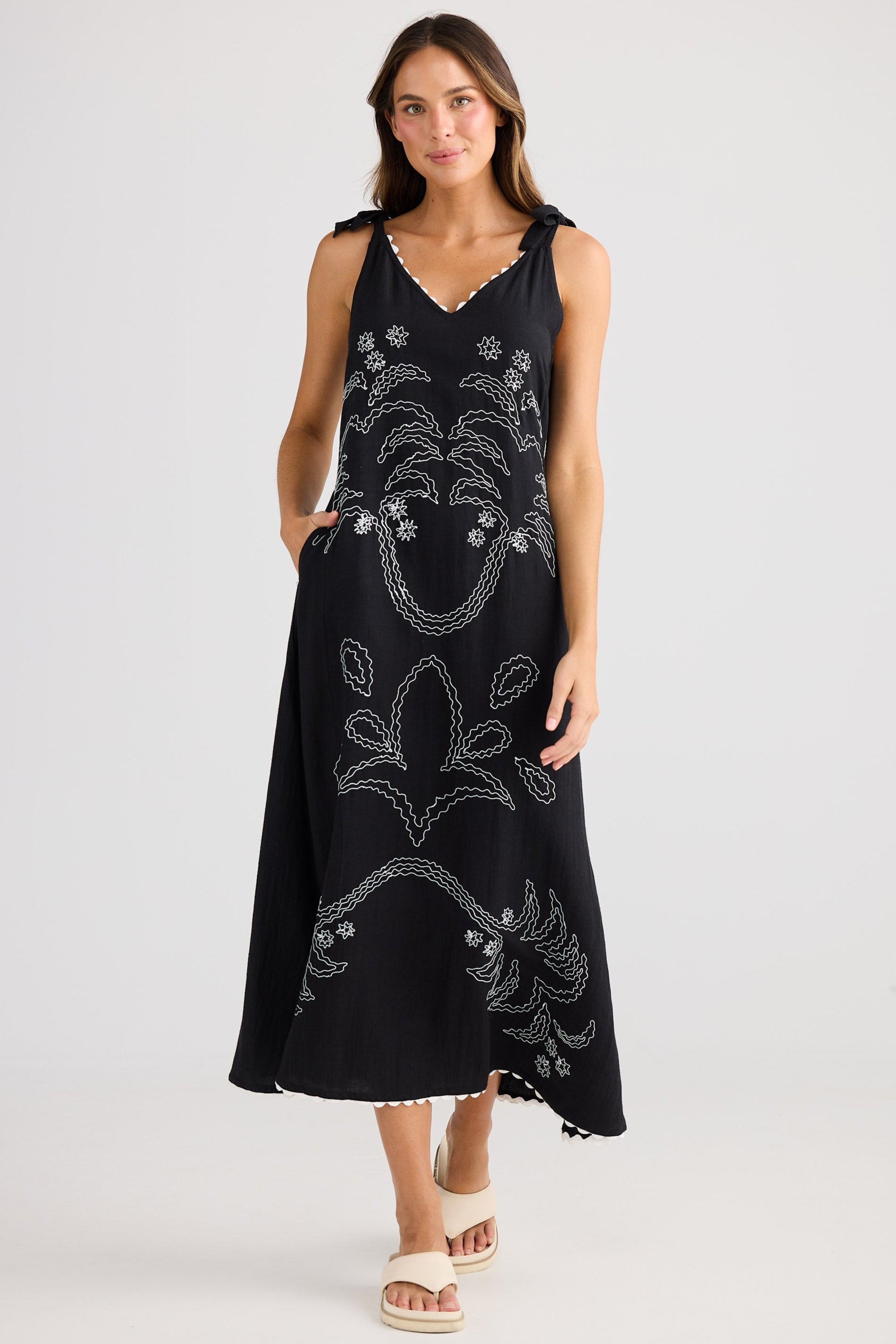 Woman wearing a black sleeveless dress with floral patterns on a white background