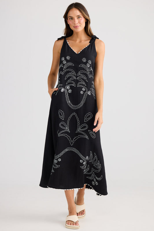 Woman wearing a black sleeveless dress with floral patterns on a white background