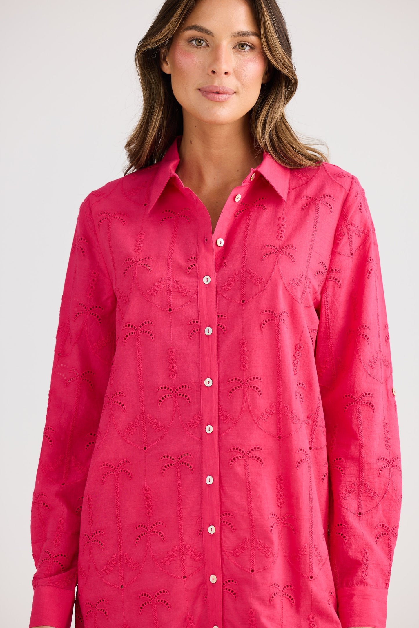 Woman wearing a bright pink shirt dress with a subtle pattern on a white background