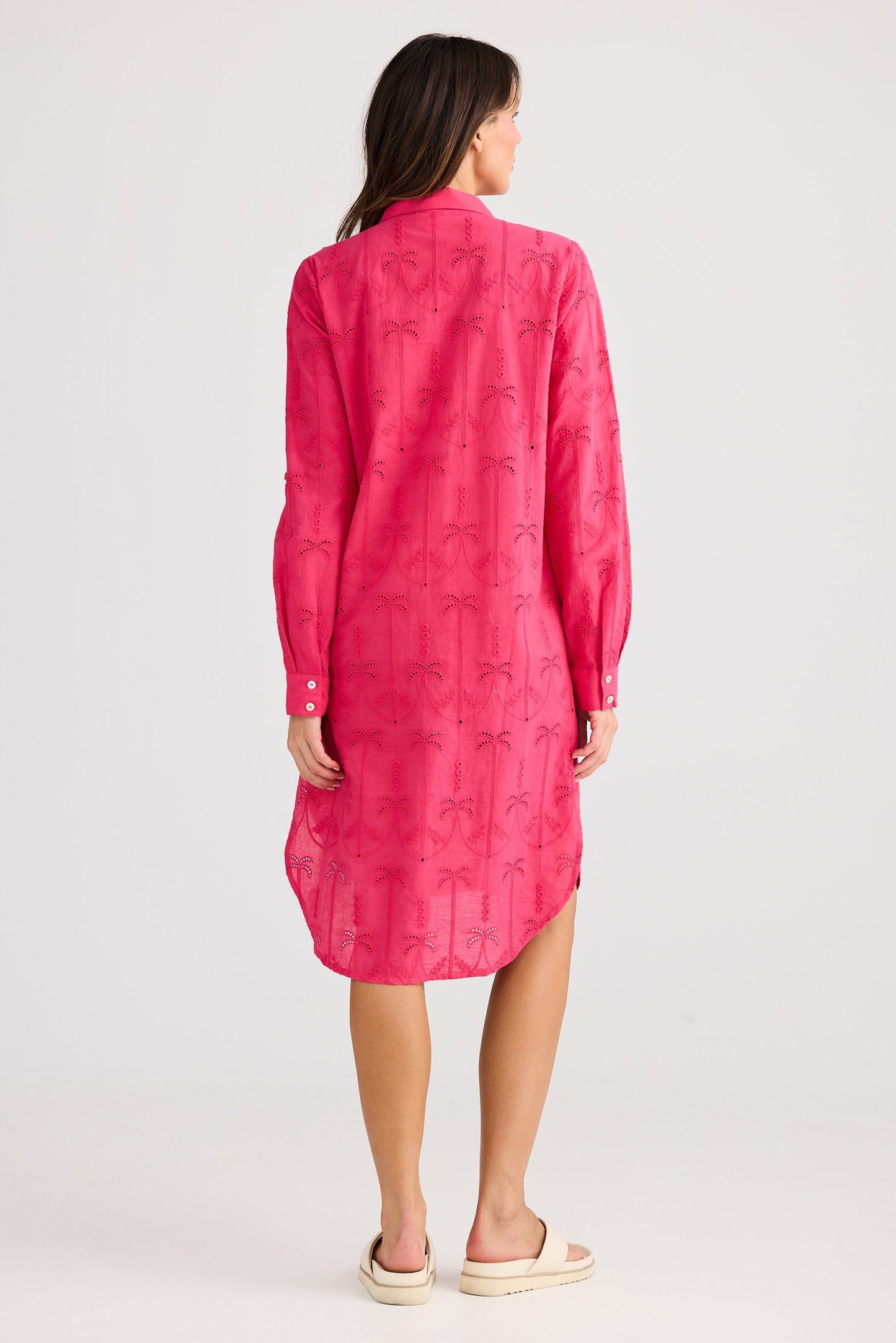 Woman wearing a pink dress with a pattern on a white background