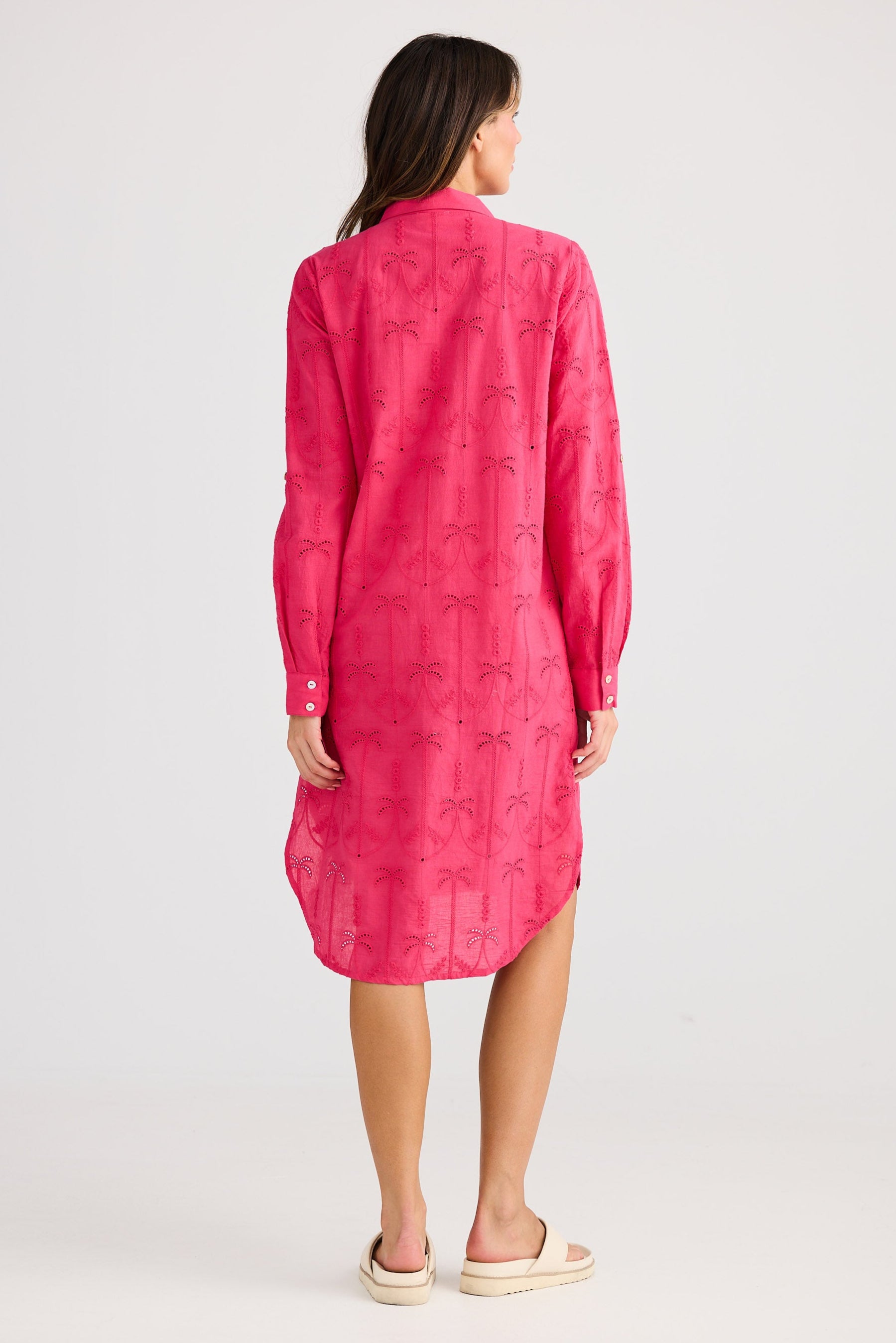 Woman wearing a pink dress with a pattern on a white background