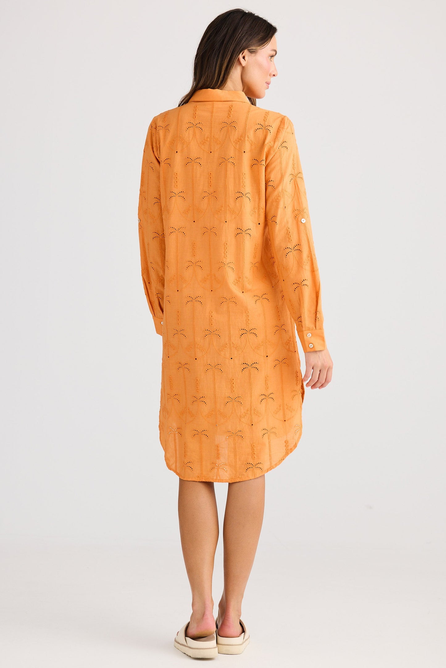 Woman wearing an orange dress with a subtle pattern on a white background