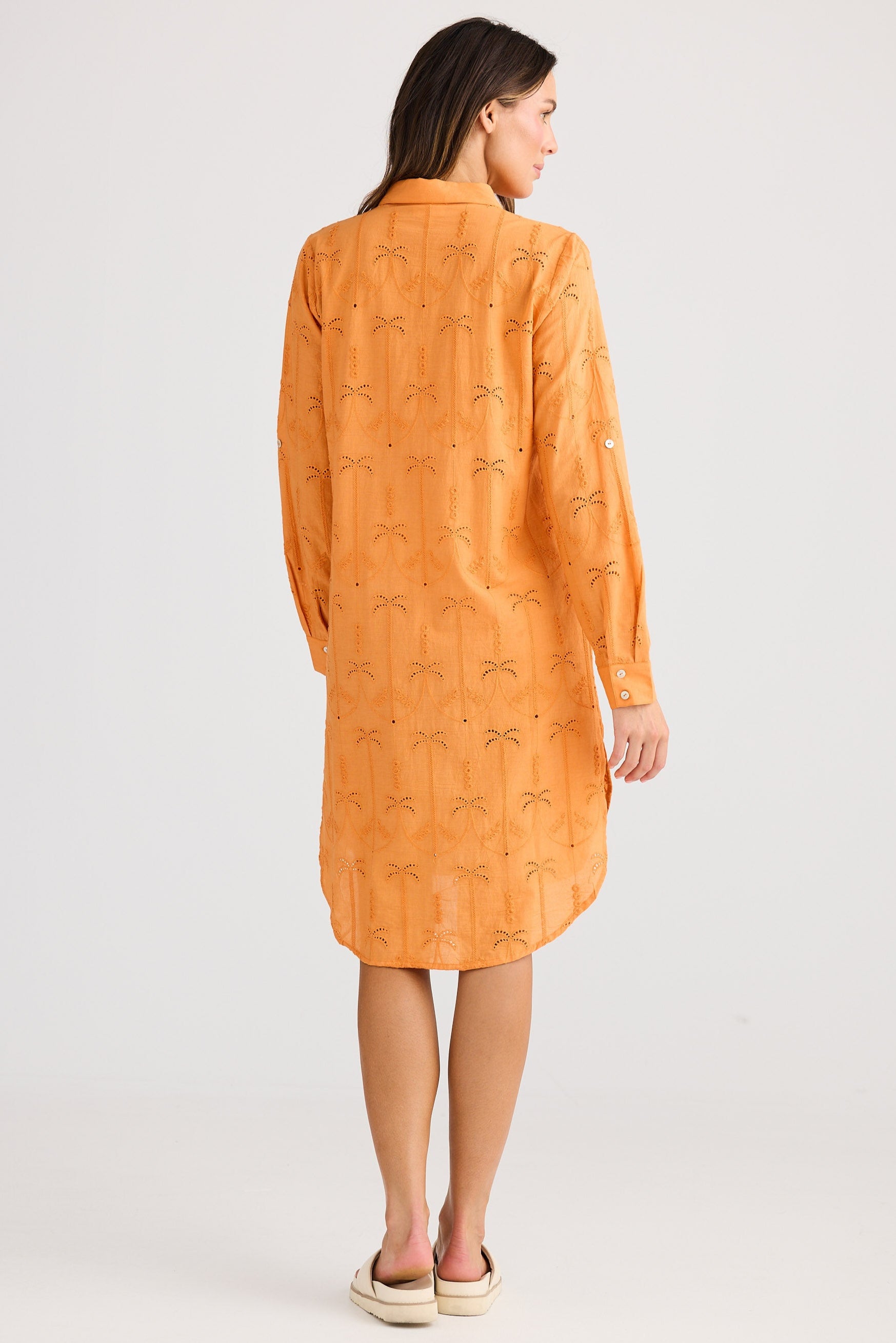 Woman wearing an orange dress with a subtle pattern on a white background