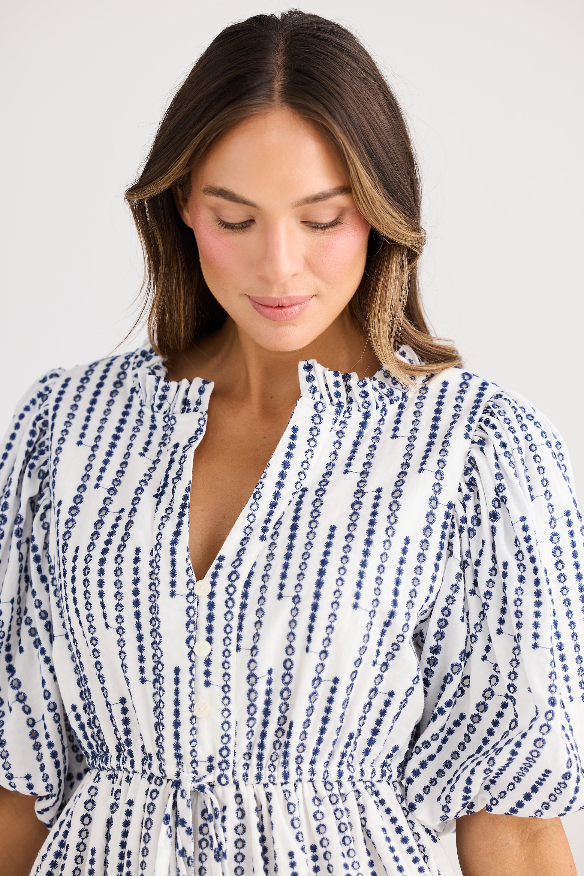 Woman wearing a blue and white patterned dress against a plain background