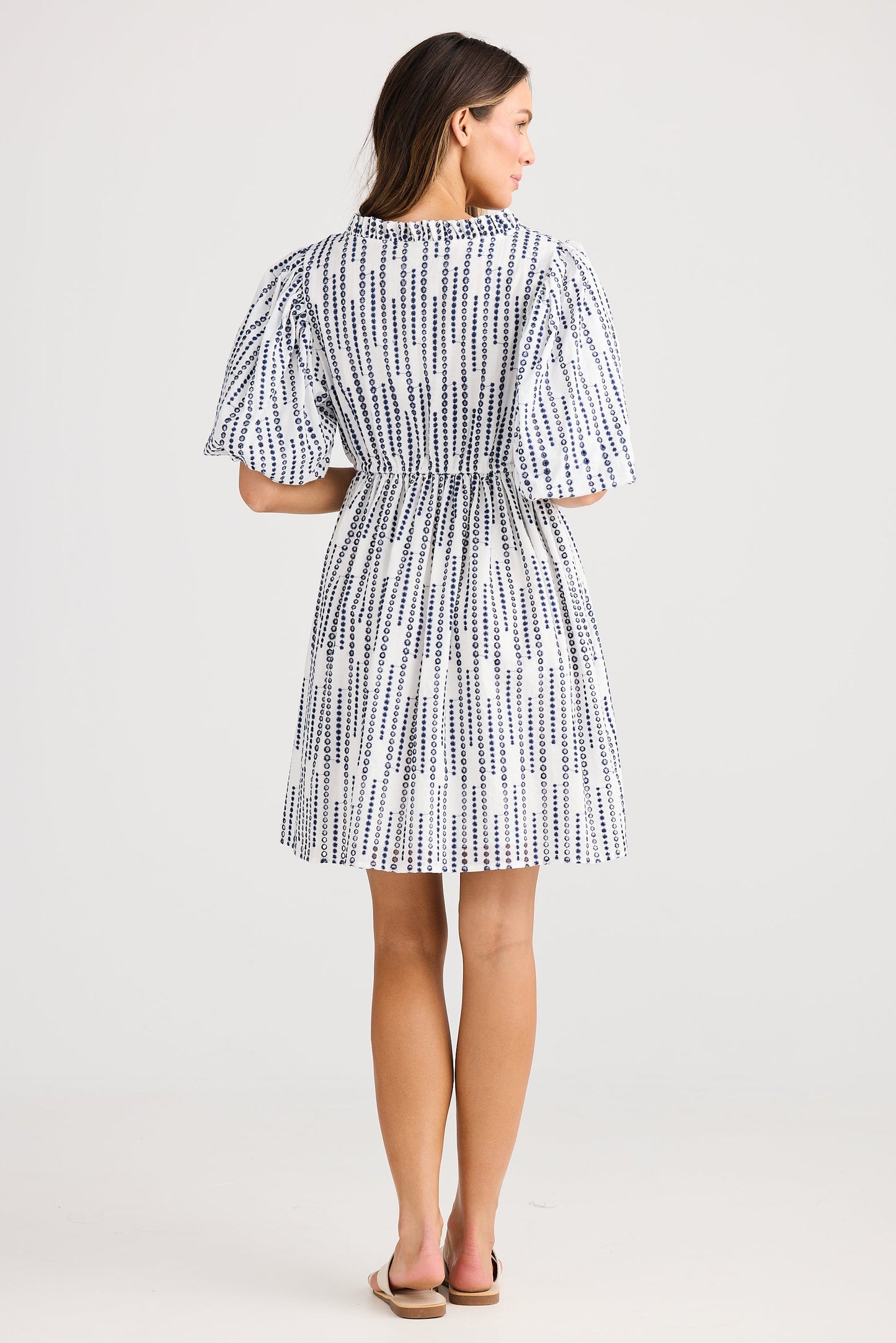 Woman wearing a blue and white patterned dress on a white background