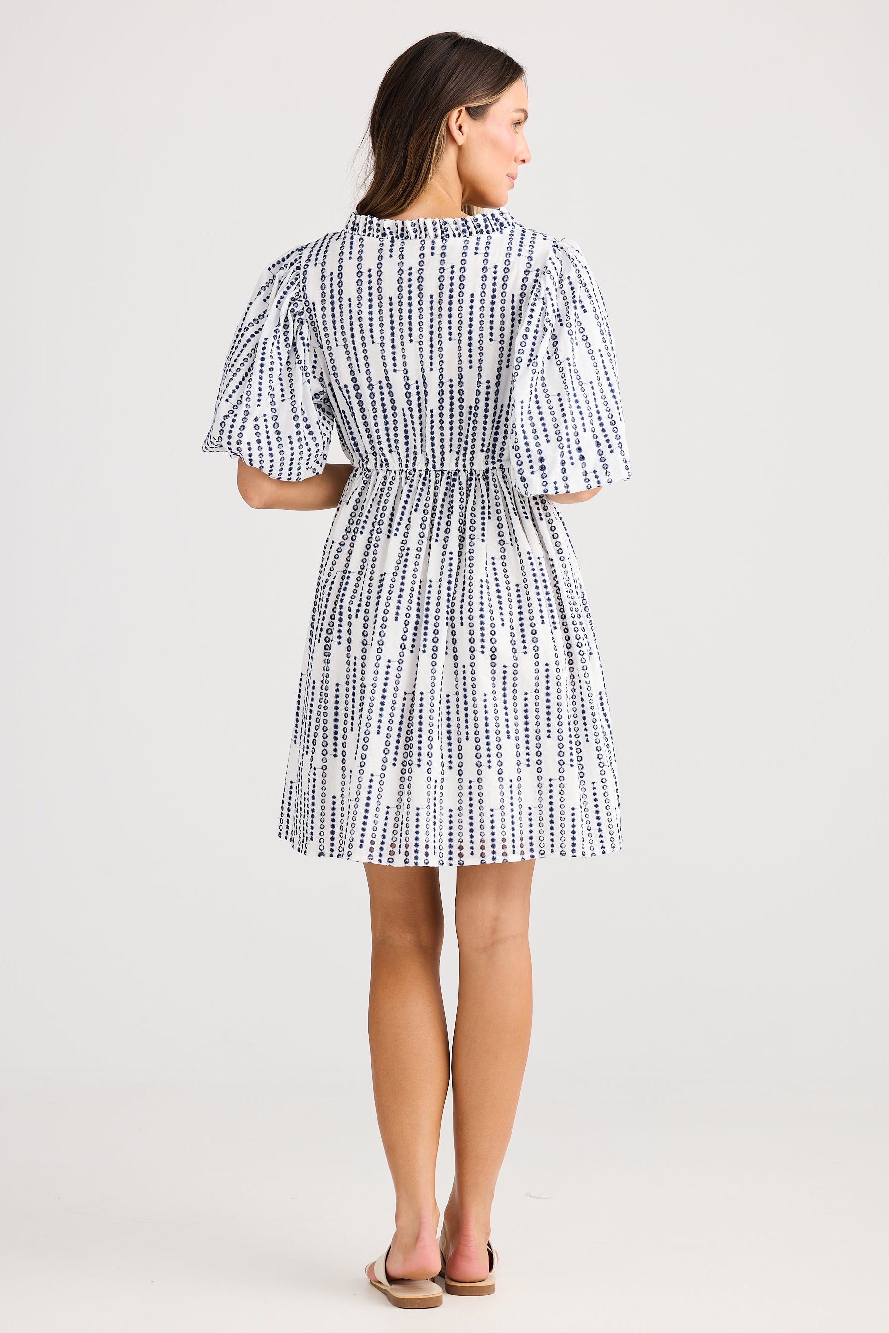 Woman wearing a blue and white patterned dress on a white background