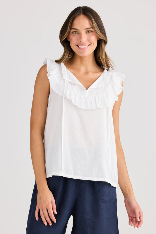 Woman wearing a white sleeveless top and navy shorts on a light gray background