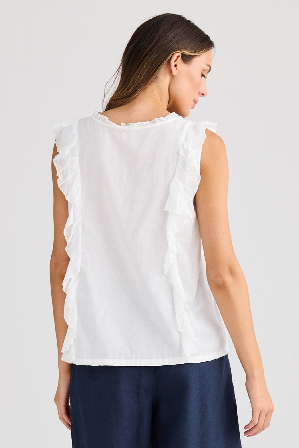 Woman wearing a white sleeveless top and navy shorts on a light gray background