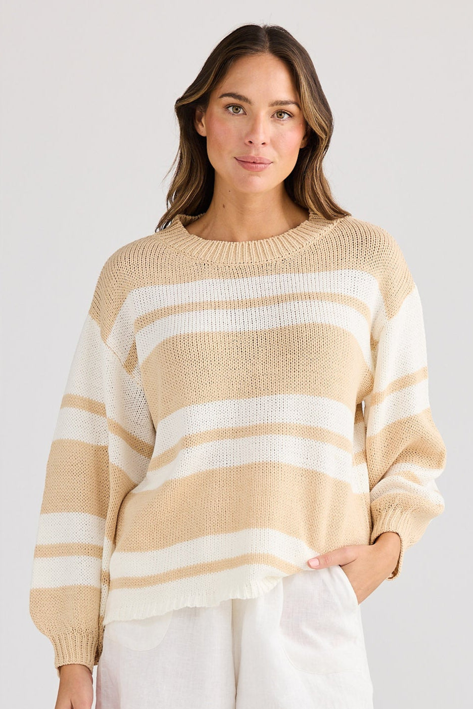 Woman wearing a striped sweater and white shorts on a plain background