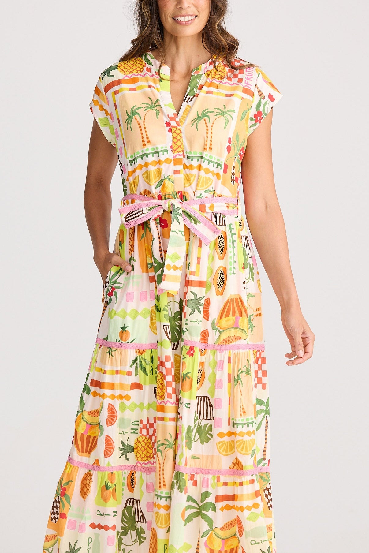 Woman wearing a colorful dress with a pineapple pattern on a white background