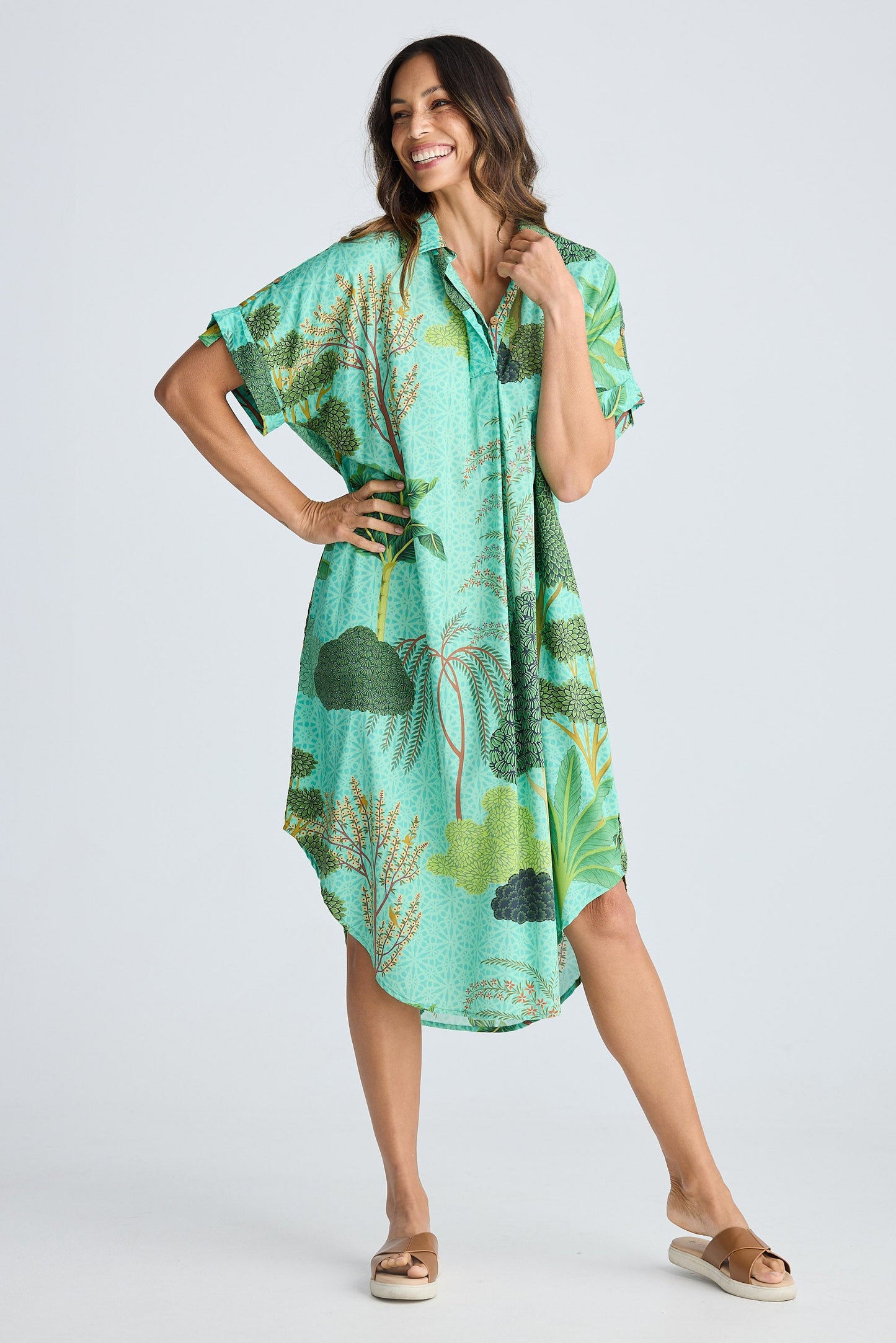 Woman wearing a green tropical print dress on a white background