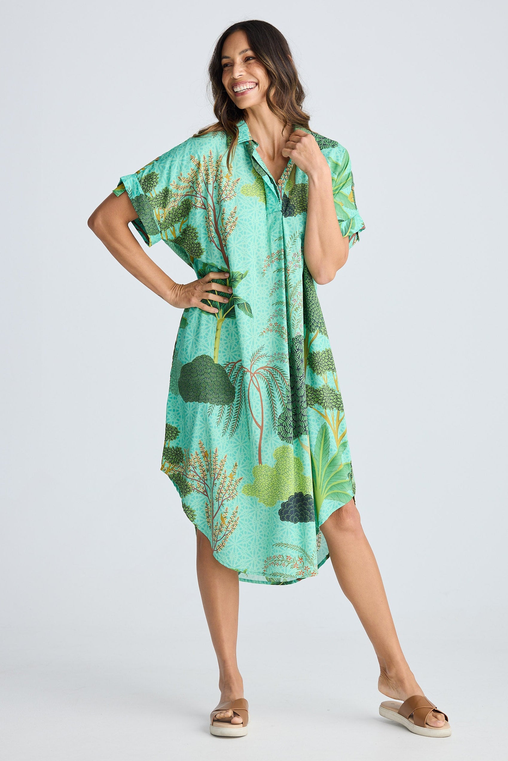 Woman wearing a green tropical print dress on a white background